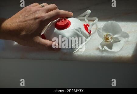 Una mano prende una maschera medica FFP2. Maschera facciale di protezione contro l'inquinamento, virus, influenza e coronavirus. Assistenza sanitaria e concetto chirurgico su covid-19 pa Foto Stock