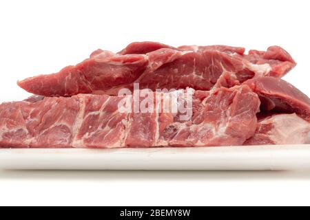 Tagli di carne di maiale cruda in contenitore bianco da vicino isolato su fondo bianco. Fette fresche senza osso Foto Stock