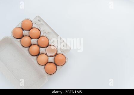 Primo piano del pacchetto di dieci uova brune e un uovo rotto sul bianco Foto Stock