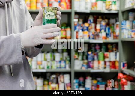 Un volontario che lavora presso una banca alimentare locale della chiesa Trussell Trust indossa guanti come DPI durante la pandemia del coronovirus Foto Stock