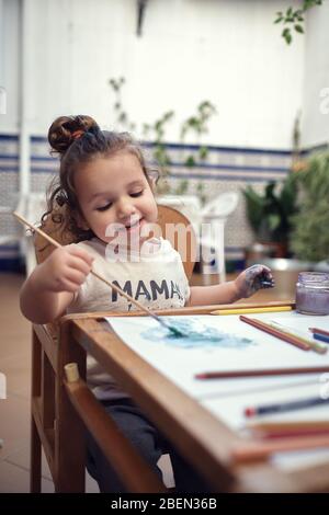 bambini che giocano in un cortile interno e dipingono con vernici ad acqua Foto Stock