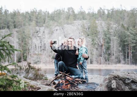 padre che scatta foto con i suoi figli mentre si gode un fuoco Foto Stock