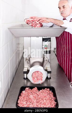 Butcher la macinazione delle carni in negozio Foto Stock