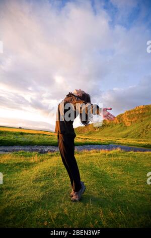 Donna cinese che si allunga al tramonto in Islanda Foto Stock