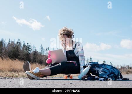 donna che parla al telefono e lavora sul suo laptop mentre pattina Foto Stock