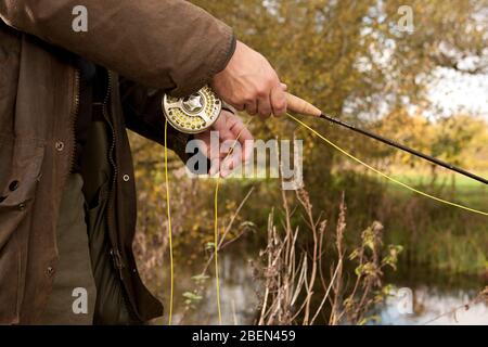 Primo piano di uomo che tiene pesca a mosca bobina nel Regno Unito Foto Stock