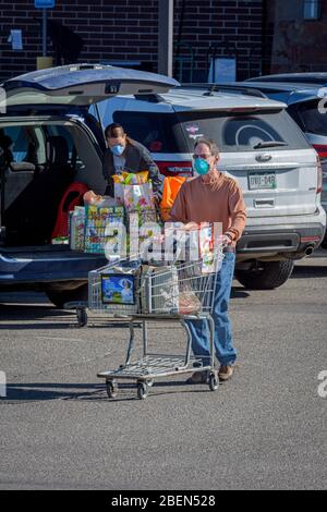 I clienti di alimentari che indossano maschere facciali protettive a causa dei generi alimentari di trasporto del virus Corona Covid-19 alle loro auto, Castle Rock Colorado USA. Foto Stock