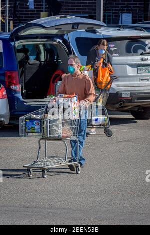 I clienti di alimentari che indossano maschere facciali protettive a causa dei generi alimentari di trasporto del virus Corona Covid-19 alle loro auto, Castle Rock Colorado USA. Foto Stock