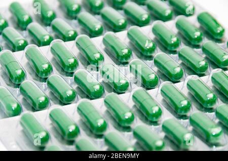 File di pillole di medicina verde in blister. Background medico. Produzione di farmaci. Concetto di alta domanda di medicinali per il trattamento del coronavirus Foto Stock