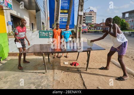 Un gruppo di ragazzi gioca a ping pong fuori casa a Lagos, Nigeria. Foto Stock