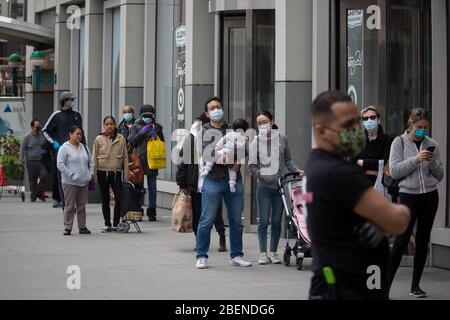 New York, Stati Uniti. 14 Aprile 2020. Le persone che indossano maschere facciali aspettano in fila per fare shopping in un negozio durante la pandemia di coronavirus nel quartiere di Brooklyn di New York, negli Stati Uniti, il 14 aprile 2020. Il numero di casi COVID-19 negli Stati Uniti ha superato i 600,000 martedì sera, secondo il Center for Systems Science and Engineering (CSSE) della Johns Hopkins University. Secondo il CSSE, il paese ha visto 602,989 casi con 25,575 morti entro le ore 6:50 (2250 GMT). Credit: Michael Nagle/Xinhua/Alamy Live News Foto Stock