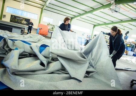 09 aprile 2020, Schleswig-Holstein, Lübeck: Due dipendenti della società di lavorazione del tessuto "geo-die Luftwerker" stanno posando un tessuto per la prossima installazione dell'artista Christo all'Arco di Trionfo di Parigi. Foto: Gregor Fischer/dpa Foto Stock