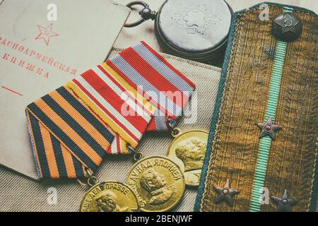 Medaglie, epaulette e ID dell'esercito di un soldato sovietico della seconda guerra mondiale, sfondo del giorno della vittoria. 'Libro dell'esercito rosso' - traduzione dal russo Foto Stock