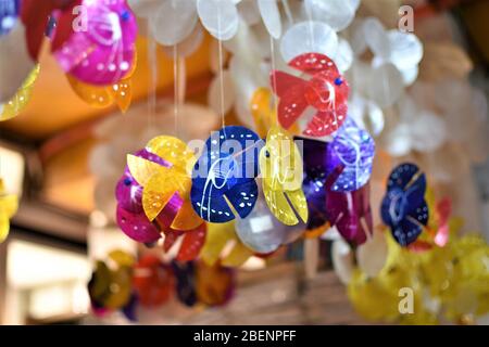 Le colorate frittelle di pesce fatte di conchiglie di Capiz o ostriche di vetro della finestra appendono all'interno di un negozio Foto Stock