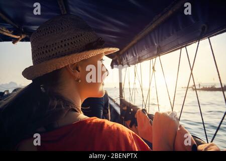 Ritratto di donna in barca dalla coda lunga con vista delle isole tropicali al tramonto nel Mare delle Andamane, Thailandia Foto Stock