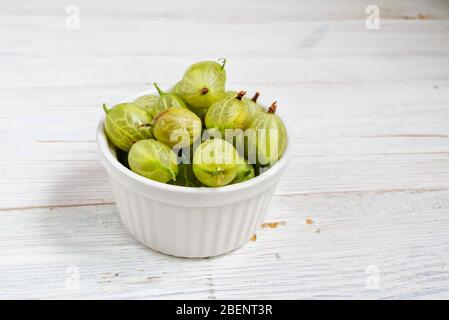 Set di uva spina biologica. Frutti di bosco in una tazza di metallo. Verde uva spina su sfondo rustico di legno. Frutti di bosco dolci e succosi. Vista dall'alto. Foto Stock