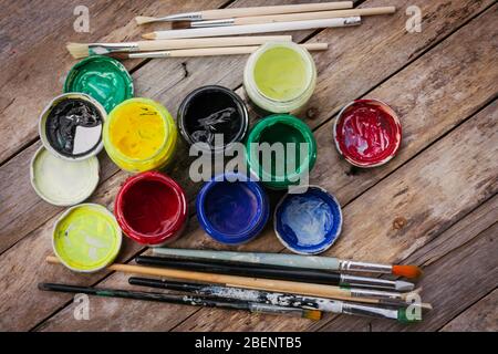 Pennelli e vasi di pittura dell'artista con vernice acrilica su sfondo di legno.sfondo hobby di pittura. Pittura concetto di arte. Foto Stock