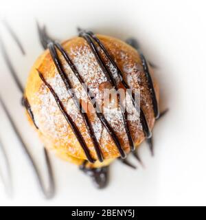 Profiterolo, una palla di pasta choux francese ripiena con un tipico dolce e umido ripieno di gelato alla vaniglia, caramello salato, salsa al cioccolato Foto Stock