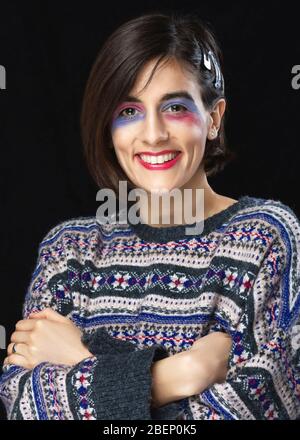 Donna con make up creativo e maglione colorato posa in studio. Modello di moda in studio. Foto Stock