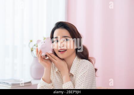 Ritratto closeup felice, sorridente donna d'affari, tenendo rosa piggy banca Foto Stock