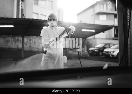 Addetto alla disinfezione in tuta con maschera N95 e occhiali protettivi.dispositivi di protezione privati (DPI).decontaminazione dell'area in quarantena.Co Foto Stock