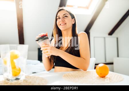 Donna sana in sportswear bere spremuta d'arancia dolce frullato dopo la casa workout.Vitamin supplement.After esercizio shaker meal.Weight perdita di fitness Foto Stock