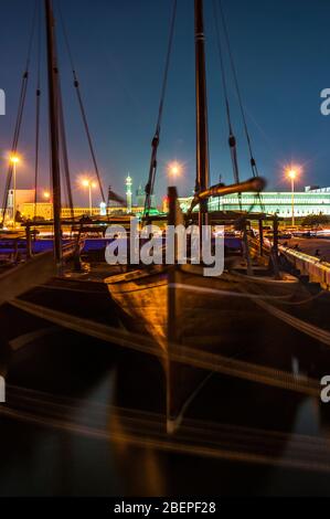 Barche tradizionali di fronte al Amiri Diwan e Grande moschea sul lungomare di Doha di notte. Foto Stock