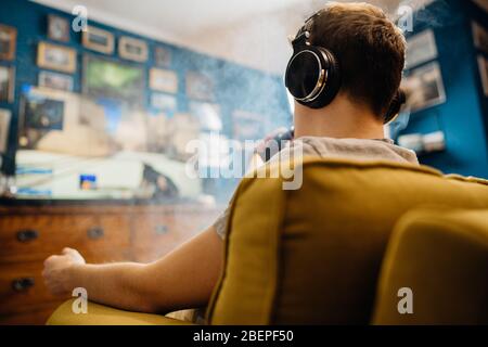 Giovane uomo gamer inalazione di un vapore con sigaretta elettronica.Vape sapore liquido chemicals.Use di e-sigarette in home.Smoking e vaporing negativo Foto Stock