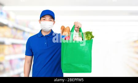 Uomo igienico che indossa la maschera medica che tiene la borsa della spesa della drogheria nel supermercato che offre il servizio di consegna domestico Foto Stock