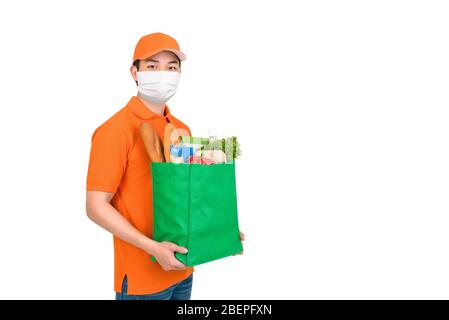Uomo igienico che indossa maschera medica che trasporta la borsa della spesa della drogheria del supermercato che offre il servizio di consegna domestico isolato in fondo bianco Foto Stock