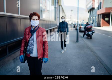 Donna anziana con maschera facciale e guanti in tessuto protettivo. Protezione contro le infezioni da malattie da herder da coronavirus COVID-19. Nonna in pensione Foto Stock