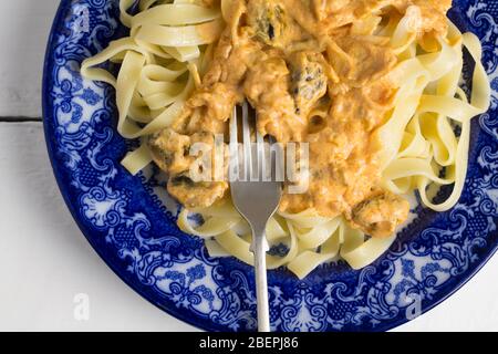 Piatto di pasta fettucina con cozze cremose e salsa di formaggio in piatto blu e bianco - immagine ravvicinata dall'alto Foto Stock