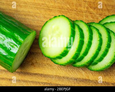 Fette di cetriolo e cetriolo su un tagliere di legno Foto Stock