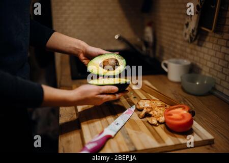 Taglio di avocado a casa kitchen.Making insalata di pollo fatta in casa.Avocado insalata sana ingrediente.salutare keto / paleo alimentare diet.Ricetta per guacamole o. Foto Stock