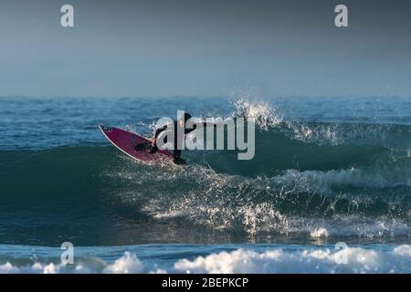 Un surfista a cavallo di un onda al Fistral a Newquay in Cornovaglia. Foto Stock