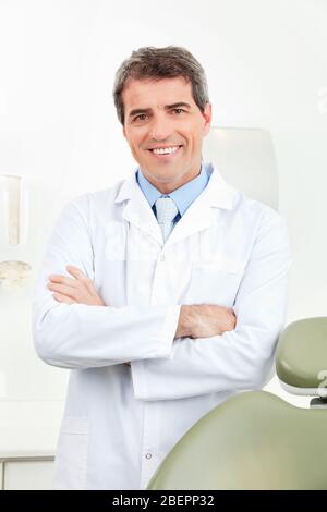 Medico sorridente in cappotto bianco in pratica Foto Stock