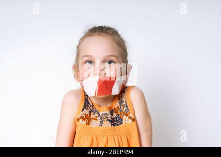 Modello biondo in blusa arancione che posa isolato su bianco. La sua bocca legata da bianco e rosso avvertimento nastro. Coronavirus Foto Stock