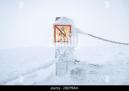 Nessun segnale di pericolo che avverte i turisti di tenerli al sicuro nel parco nazionale di Krkonose. Segnale di avvertimento coperto di neve. Foto Stock