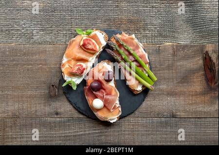 Spuntini bruschette. Varietà di deliziosi panini sullo sfondo rustico in legno, vista dall'alto. Foto Stock