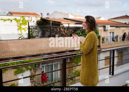 Giovane donna in quarantena applaudendo per sostenere gli operatori sanitari Foto Stock