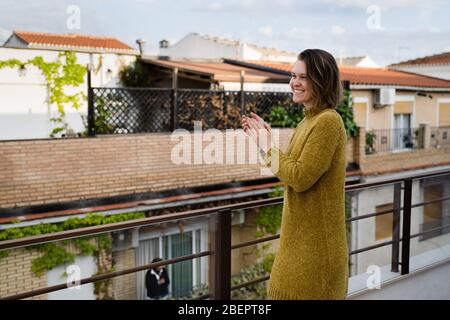 Giovane donna in quarantena applaudendo per sostenere gli operatori sanitari Foto Stock