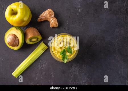 Frullato verde appena preparato con verdure, frutta, erbe e verdure su sfondo scuro. Spazio di copia Foto Stock