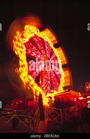 Fiera. Vista notturna della ruota panoramica rotante con persone. Foto Stock