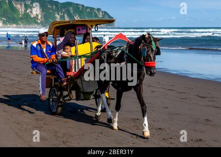 Persone indonesiane che si godono UN giro in carrozza a cavallo sulla Parangtritis Beach, Yogyakarta, Indonesia. Foto Stock