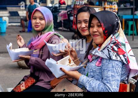 Giovani indonesiani Donne che mangiano cibo di strada, Malioboro Street, Yogyakarta, Indonesia. Foto Stock