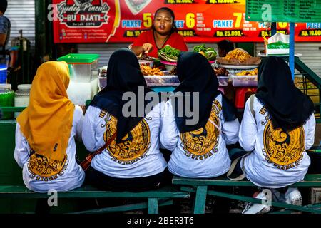 Giovani indonesiani Donne che mangiano cibo a una Street Food Stall, Malioboro Street, Yogyakarta, Indonesia. Foto Stock