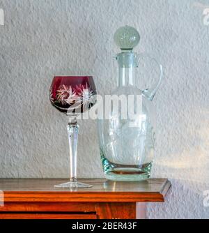 Vetro e decanter antichi rossi di vino bohémien su armadio Foto Stock