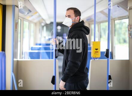 Stoccarda, Germania. 15 aprile 2020. ILLUSTRAZIONE - UN giovane indossa un respiratore di categoria FFP2 in un veicolo leggero su rotaia (foto posata). Si sta discutendo l'obbligo di indossare una maschera per bocca e naso in pubblico come possibile misura per allentare gradualmente le restrizioni imposte per combattere la pandemia di coronavirus. Credit: Christoph Schmidt/dpa/Alamy Live News Foto Stock