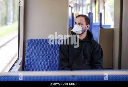 Stoccarda, Germania. 15 aprile 2020. ILLUSTRAZIONE - UN giovane indossa un respiratore di categoria FFP2 in un veicolo leggero su rotaia (foto posata). Si sta discutendo l'obbligo di indossare una maschera per bocca e naso in pubblico come possibile misura per allentare gradualmente le restrizioni imposte per combattere la pandemia di coronavirus. Credit: Christoph Schmidt/dpa/Alamy Live News Foto Stock