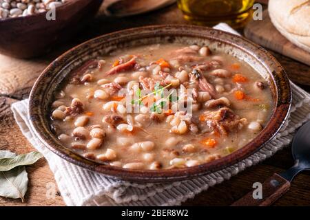 Una ciotola di deliziosa zuppa di fagioli fatta in casa con prosciutto affumicato e carote. Foto Stock